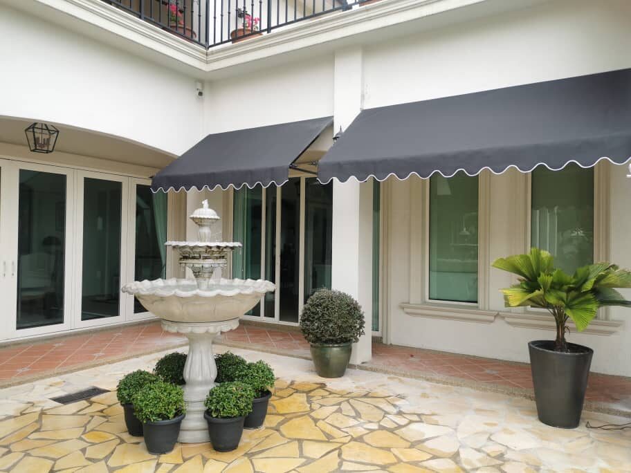 Fixed canopy over a paved courtyard patio with a fountain at a Malaysian home