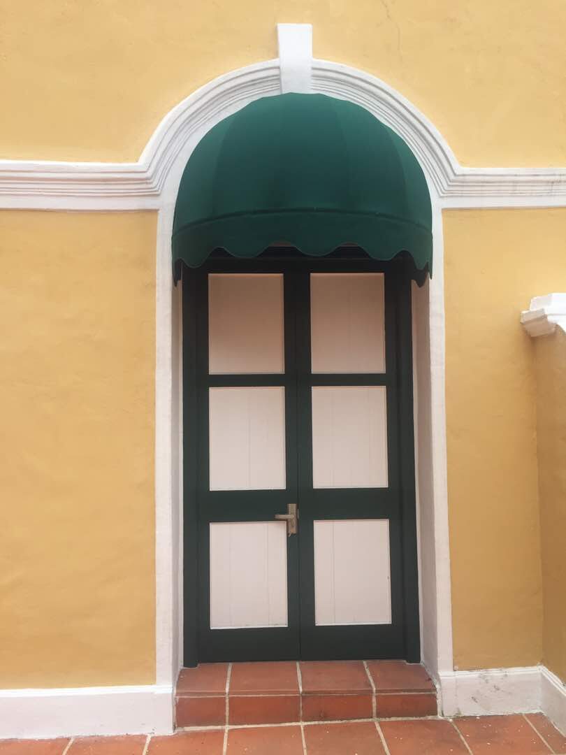 Green domed fixed canopy over an arched timber door entrance