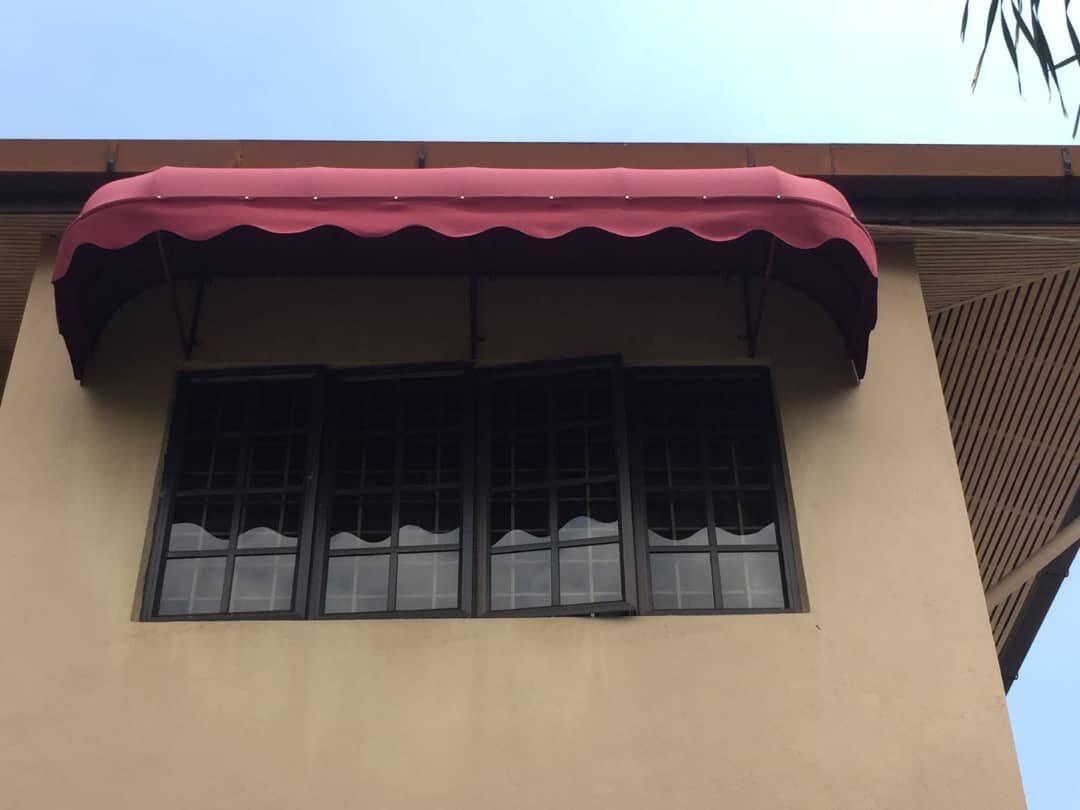 Burgundy curved fixed canopy over a window on a Malaysian home
